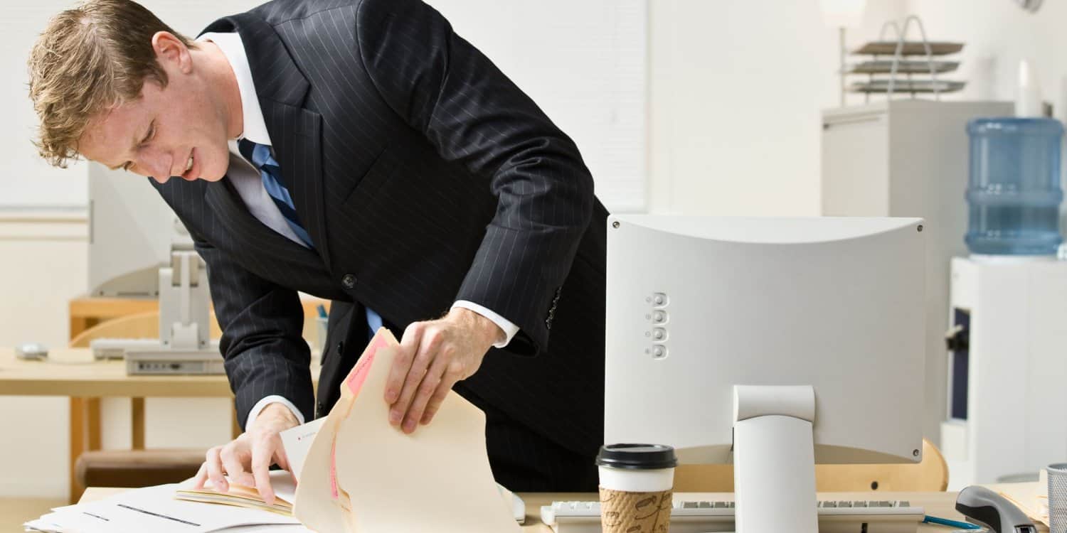 Image of a man in an office looking for a lost certificate of incorporation of his desk