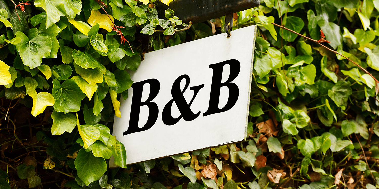 Image of a B&B sign protruding from an ivy-covered wall, illustrating the concept of starting a bed and breakfast business in the UK.