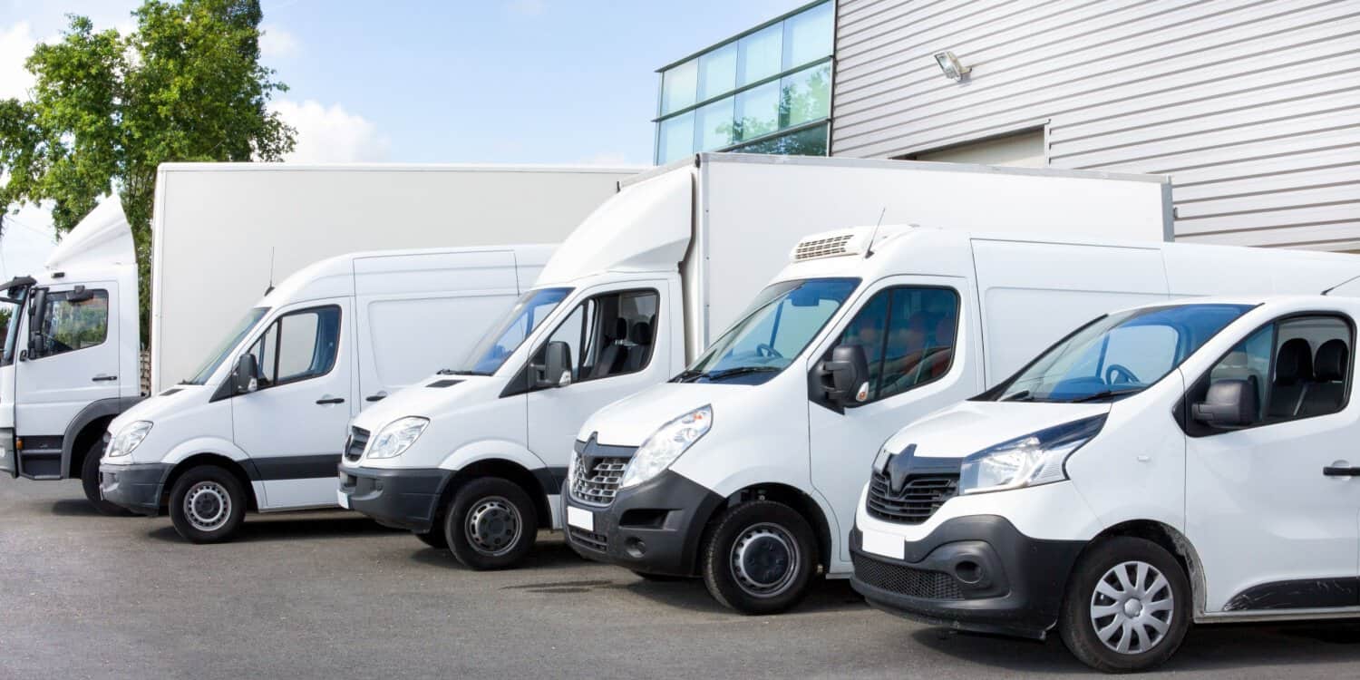 A row of white vans parked outside of a workplace