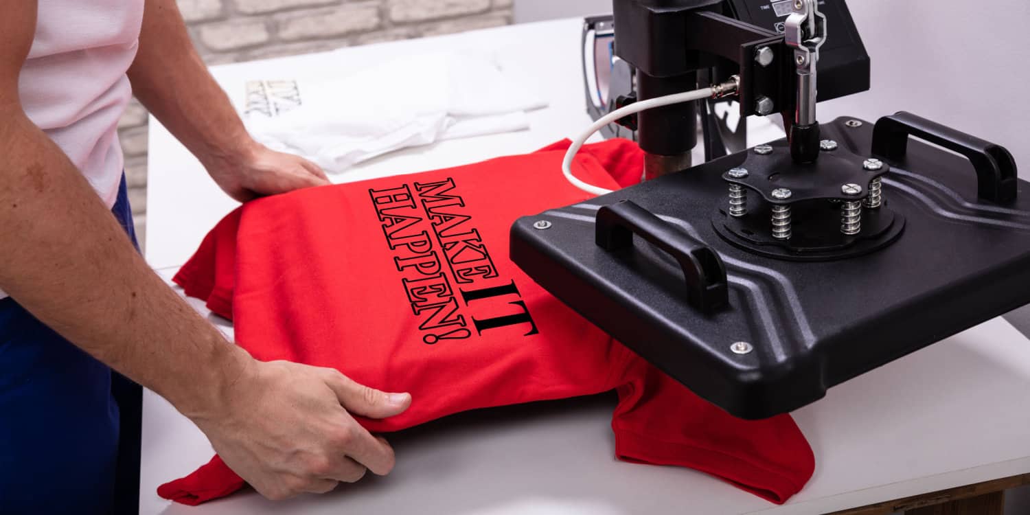 Print-on-demand business owner making a print on a red t-shirt in his workshop.
