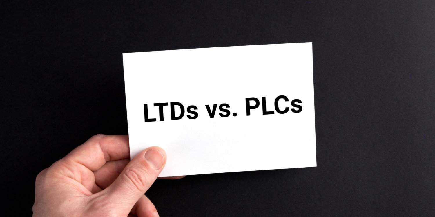 Male hand holding a white card with 'LTDs vs. PLCs' displayed on it in black text, against a black background.