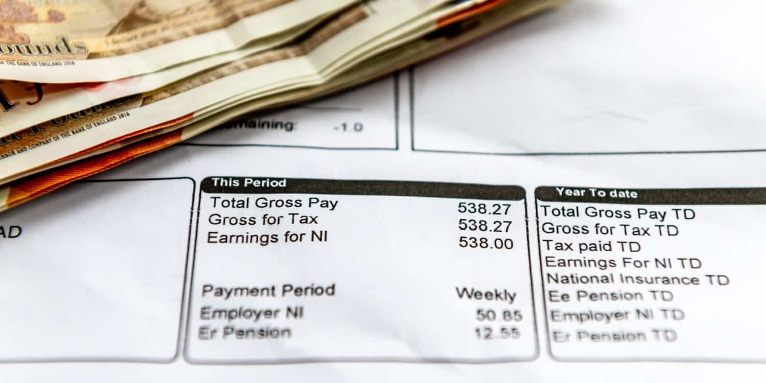 A employee payslip showing earnings, and tax and National Insurance deductions with some bank notes.